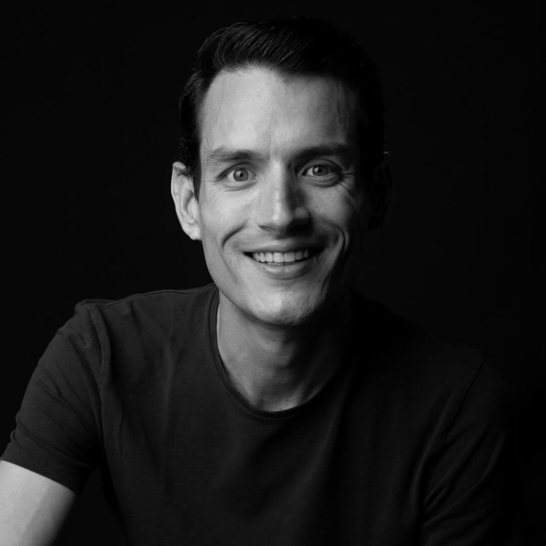 Black and white portrait of Sebastián Delsalto, founder of Daleki Trade, smiling against a dark background